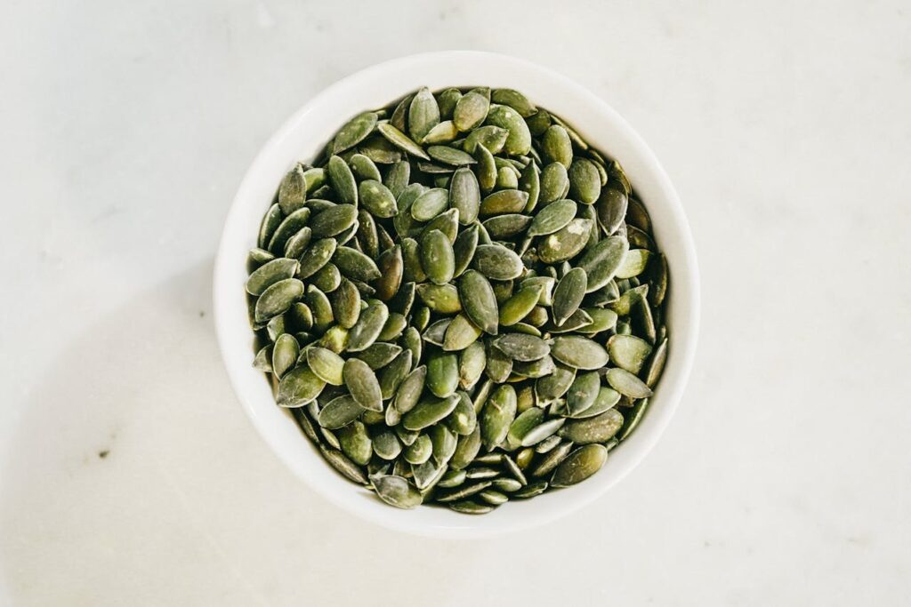 A bowl of pumpkin seeds, a high-protein, low-carb snack ideal for diabetes-friendly eating and blood sugar control.